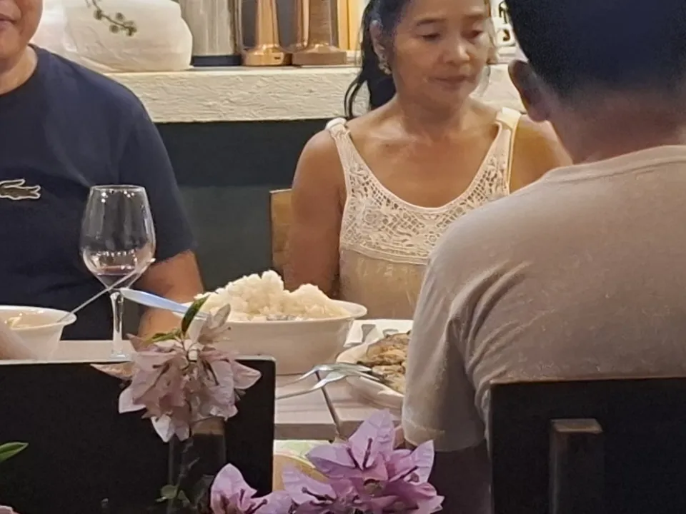 Guests gathered around the table at Kape Parola in the evening under fairy lights and hanging plants
